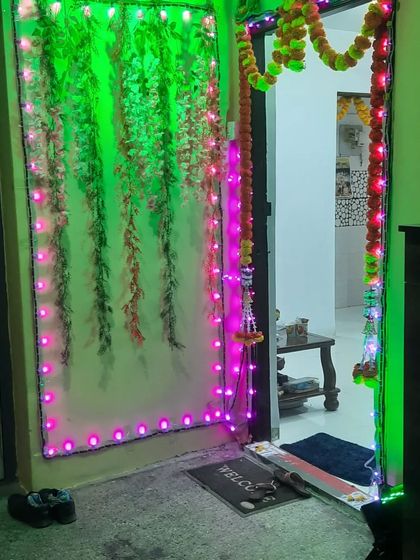 Simple yet festive door decoration for a home event, using artificial leaf garlands and colorful LED strip lights.