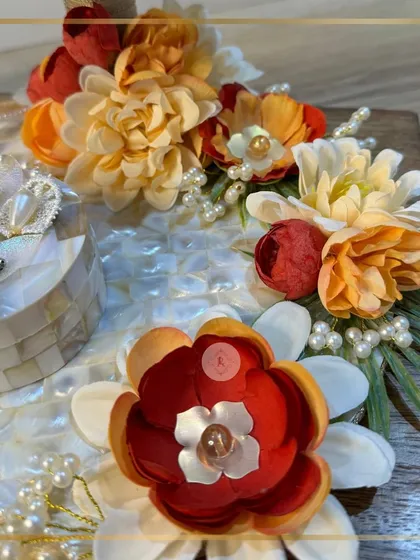 The texture and detail of our handcrafted flowers. We carefully select and arrange each bloom, like these burnt orange and red flowers, to create a rich and beautiful composition on the mother-of-pearl platter.
