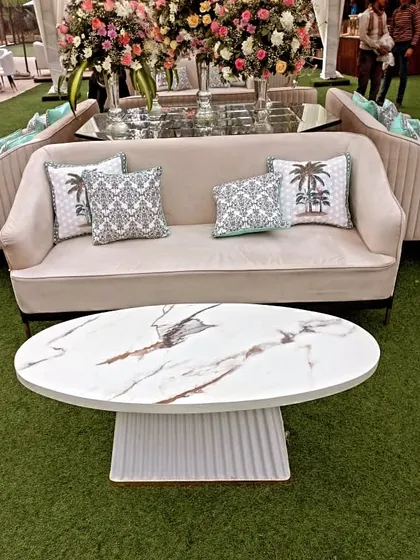 A close-up of the modern and elegant lounge furniture we provide for our events. This setup includes a plush beige sofa with stylish cushions and a contemporary marble-topped coffee table, perfect for a chic guest seating area.