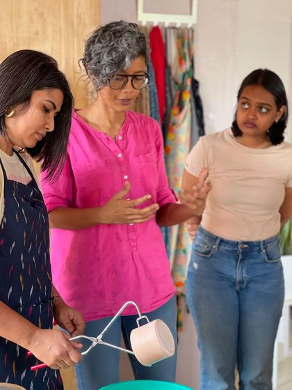 A candid moment of conversation and learning during a glazing session, where students get to see their pieces come to life with color.