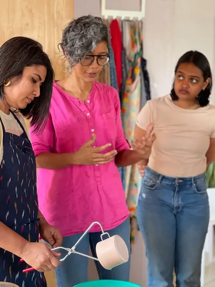 A candid moment of conversation and learning during a glazing session, where students get to see their pieces come to life with color.