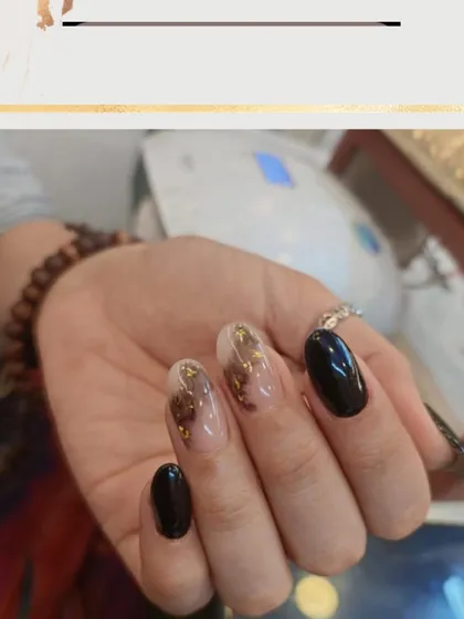 An edgy and sophisticated design. This set combines solid black nails with accent nails featuring a sheer base and a smoky black and gold foil design.