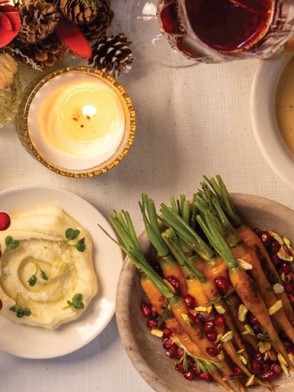 A cozy, candlelit corner of our holiday table, featuring creamy hummus and glazed carrots. It’s all about creating a warm and inviting atmosphere.