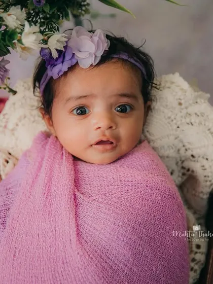 This little girl is wide-eyed and ready for her photoshoot. The purple swaddle and floral theme create a lovely, feminine portrait.