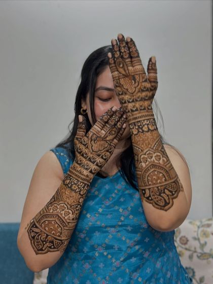 A happy bride peeking through her intricately designed hands. This is a classic bridal pose!