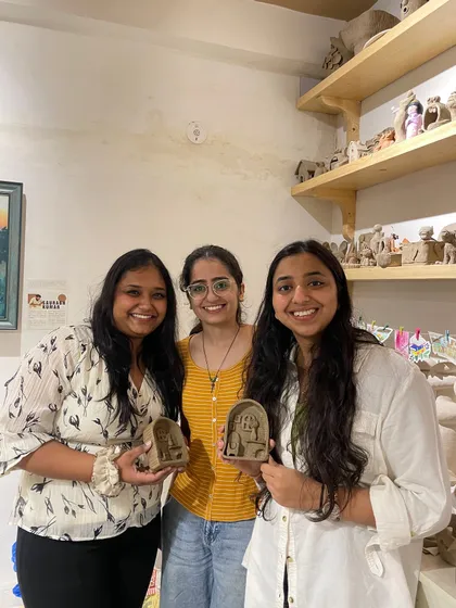Three friends are all smiles with the small clay sculptures they created during a fun group session.
