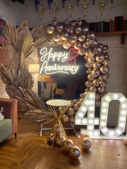 A detailed view of the 40th-anniversary decoration. The combination of a metallic balloon arch and dried palm leaves offers a modern, bohemian-inspired look for a milestone event.