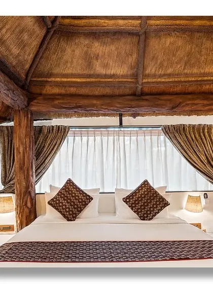 A bedroom in a garden villa, with a rustic, log-style four-poster bed that creates a cozy and natural feel. The design is perfect for a resort that blends luxury with nature.