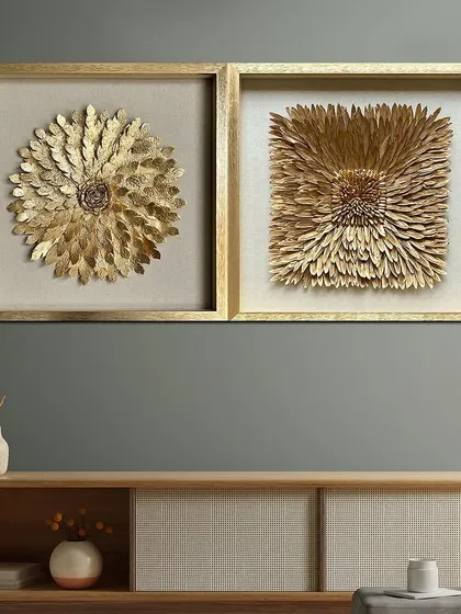 A stunning shadow box featuring an array of golden petals meticulously arranged to form vibrant, textured flowers. This set of two is a classic addition that highlights any wall with a touch of opulence.