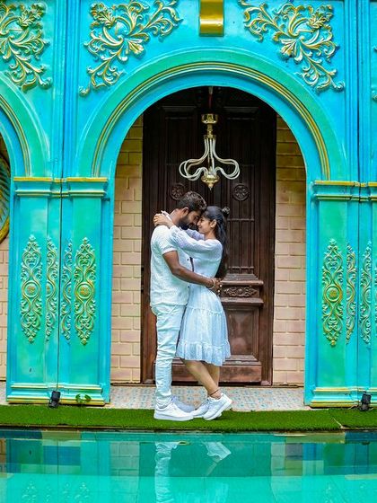 A romantic embrace in front of a vibrant blue and gold building with lion head carvings, adding a touch of fantasy and royalty.