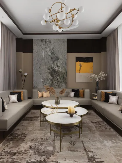 A formal living area designed with a symmetrical U-shaped seating arrangement, perfect for hosting large groups. The neutral tones are accented with black and gold, and large-scale abstract art adds a dramatic touch.