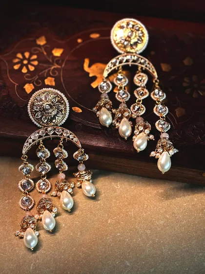 A pair of classic chandbali earrings, featuring a crescent design with cascading polki and pearl drops. Timeless, elegant, and perfect for any celebration.
