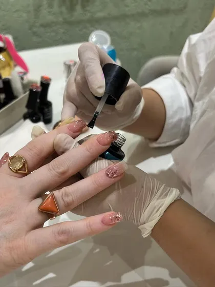 Holiday nails in the making! Applying a coat of sparkling glitter polish for a festive and glamorous finish.