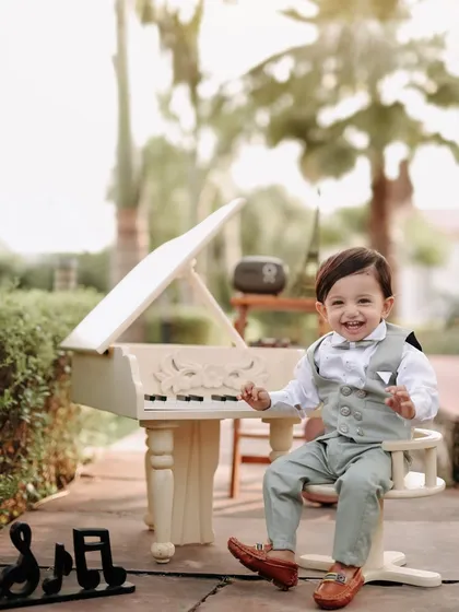 A big, welcoming smile from our little musician. He is clearly having a wonderful time at his outdoor piano, and his happiness is contagious.