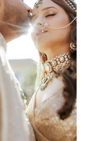 A sun-kissed moment of pure bliss. The light catches the bride's jewelry beautifully, highlighting the exquisite craftsmanship of her polki choker and nath.