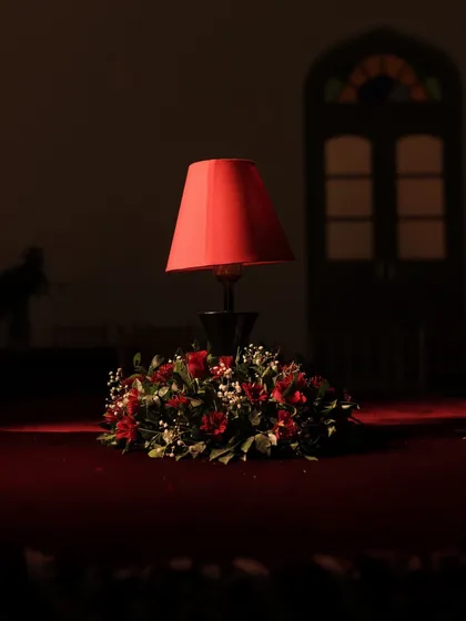 An artistic shot of a single table lamp centerpiece, its red glow illuminating the rich velvet tablecloth and creating an intimate, moody atmosphere.