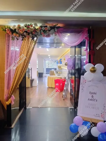 An elegant entrance for a baby shower with fabric drapes and a floral arrangement.