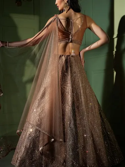 The back detail of this bronze-gold lehenga is designed to be just as captivating, with a stylish tie-up blouse and a sheer, flowing dupatta.