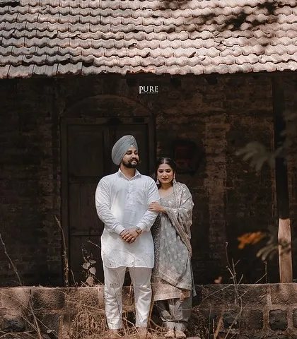 A classic portrait of Aman and Simran standing before a rustic, old-world building. The earthy tones and their traditional outfits give this pre-wedding photo a beautifully grounded and authentic feel.