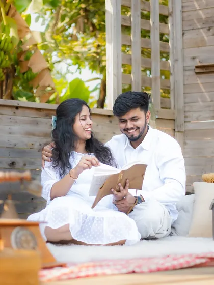 A candid shot of a couple sharing a laugh while looking at a book, showing their genuine connection in a beautifully styled setting.