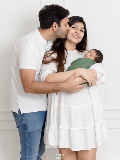 A kiss for mom from a proud new dad, while she lovingly cradles their newborn.