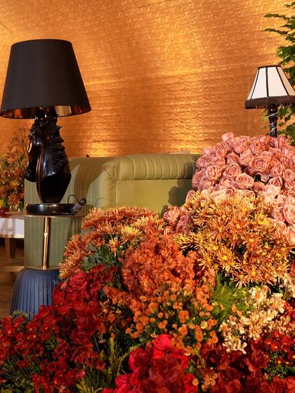 A dramatic floral installation in shades of red and orange, set against an olive green sofa.