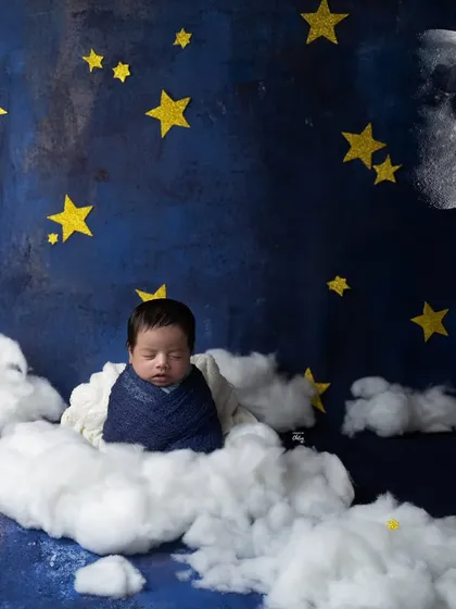 A wide shot of our "dreamland" theme, with a baby sleeping peacefully on a cloud under a starry night sky with a big, bright moon.
