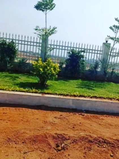 A completed section of the L&T company project, showing a new lawn and plantings along a fence line.