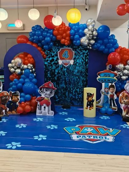 A wider view of the 'Paw Patrol' birthday decoration, showing the complete stage with all the characters and the vibrant balloon arrangement.