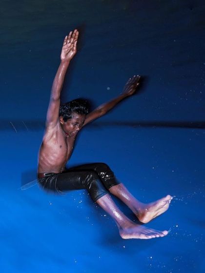 A boy is captured mid-air as he jumps into deep blue water, a dynamic and colorful image that freezes a moment of pure, uninhibited fun.