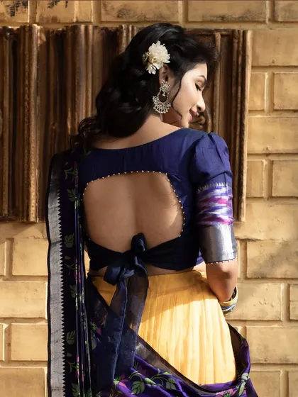 The back of the navy blue blouse features a stylish cutout with a tie-back bow, adding a contemporary element to the traditional half saree.
