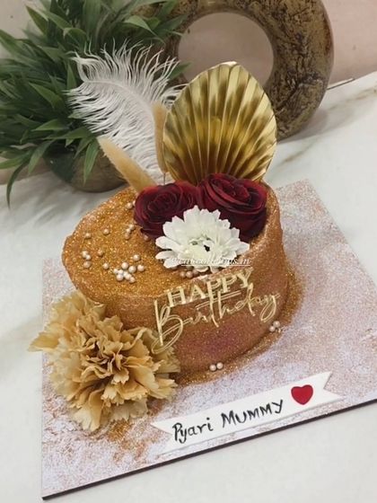 A closer look at the details on the golden glitter cake, including the custom topper and floral accents.