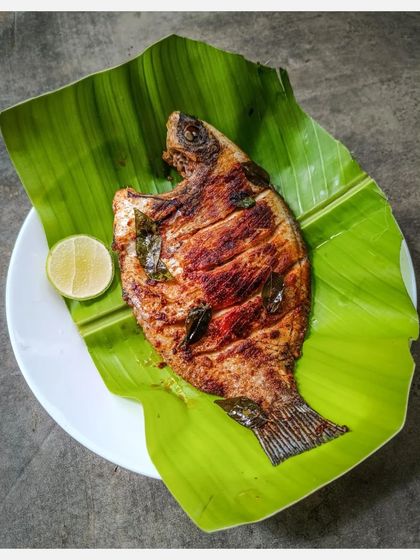 The full plate presentation of my Tawa Grilled Karimeen, served with a slice of lime on a banana leaf.