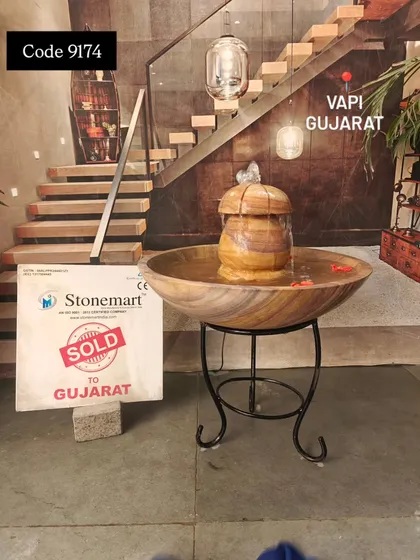 The Teak Sandstone tabletop fountain, with its warm colors, is shown here with decorative flower petals floating in the water.