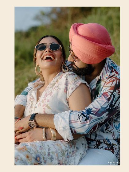 A joyful, candid shot of a couple laughing together in a field in Thailand, capturing a moment of pure happiness.