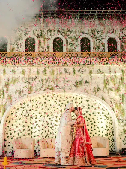 We believe in creating fairytale moments. This shot, with the couple sharing a kiss under a grand floral arch as petals rain down, showcases the cinematic and luxurious scale we bring to wedding photography.