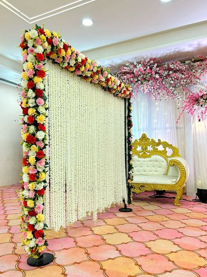 A still shot of the multi-colored Nikah backdrop rental. The contrast between the colorful flowers and the white strings creates a vibrant yet elegant look.