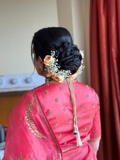 A soft, romantic bridal bun adorned with peach roses and baby's breath. This is a beautiful and delicate option for any bride.
