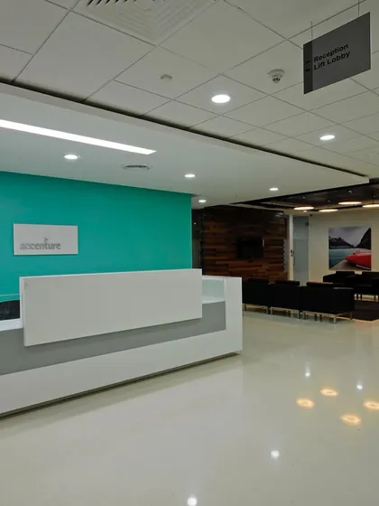 The clean and minimalist reception area for Accenture. The design uses the brand's signature teal color as an accent wall, paired with a simple white desk and bright, even lighting for a professional look.