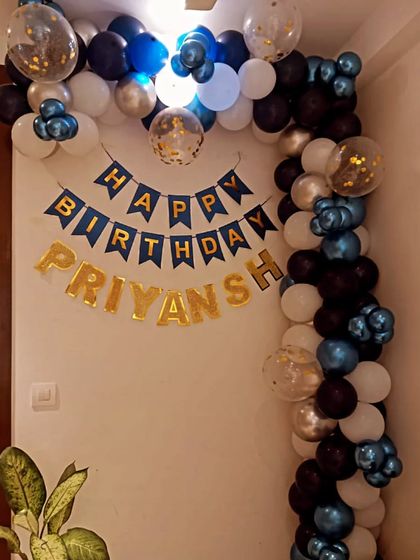 A simple and classic balloon garland in blue, black, and white for a home celebration. A 'Happy Birthday' banner and name foils complete this easy and festive look.