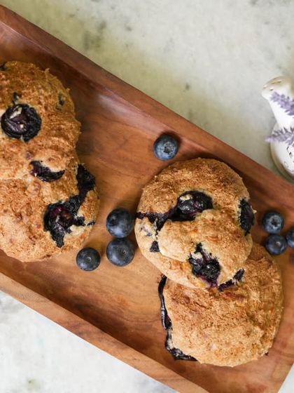 A top-down view of the blueberry cookies, scattered with fresh berries on a wooden tray.