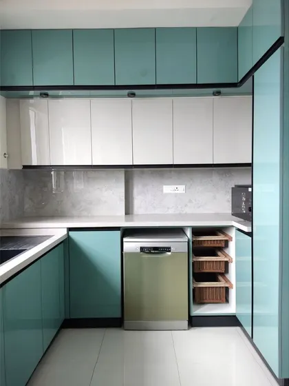 A modern kitchen is a blend of clean aesthetics and smart functionality. This bespoke kitchen in a vibrant teal features high-gloss cabinetry, integrated appliances, and ample counter space, designed for a seamless culinary experience in a contemporary Bengaluru home.