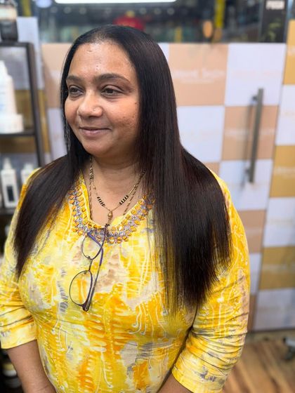 A happy client smiling after her Royal Nanoplastia treatment. Her hair is visibly smoother, straighter, and healthier, giving her a fresh and confident new look.