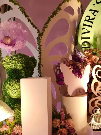 Detail shot of the luxury decor, featuring a topiary bear, large cutout butterfly wings, and oversized fabric flowers.