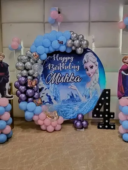 A 'Frozen' themed 4th birthday party with a circular backdrop, character cutouts, and a balloon garland.