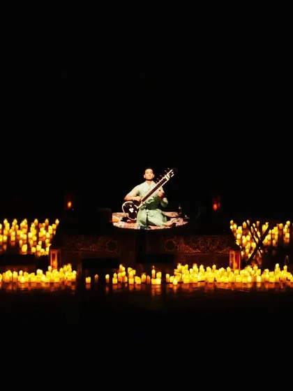 A solo moment on stage, surrounded by candles. This setup is central to the 'Sitar for Mental Health' experience, creating an atmosphere of intimacy and focus, no matter the size of the venue.
