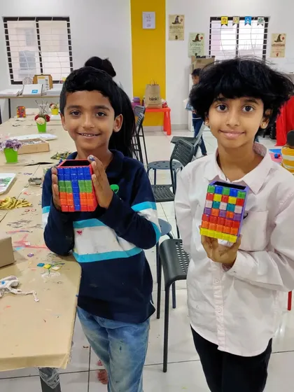 Two boys happily showing the camera the colorful pen stands they decorated with mosaic tiles.