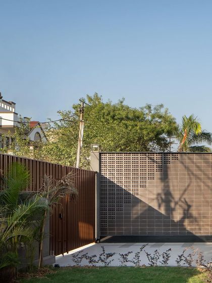 A view of the main gate and boundary wall. The design uses earthy tones and natural materials to create a serene ambiance, offering a peaceful contrast to the surrounding city.