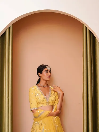 A chic and minimal look, perfect for a bridesmaid or for a bride's smaller event. We styled this vibrant yellow lehenga with a simple maang tikka and necklace, letting the color and craftsmanship of the outfit shine.