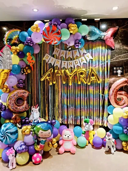 A vibrant and colorful mermaid and candy-themed party for a 6th birthday. I used a rainbow streamer backdrop, a multi-colored balloon arch with fun elements like a mermaid tail and candy foils, and character props to create a playful underwater world.